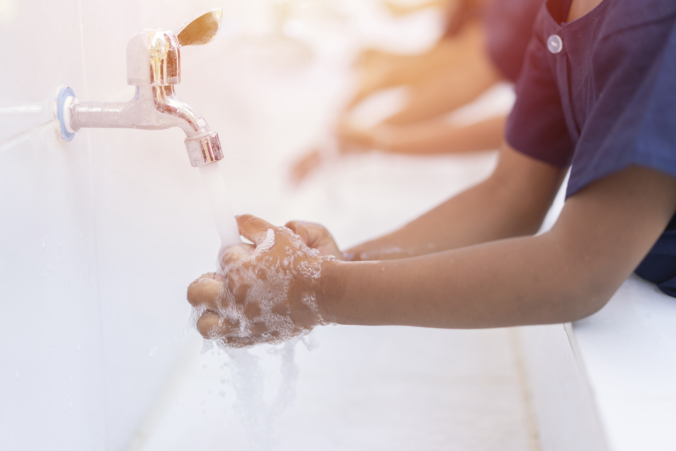 Children washing hands with soap under the faucet with water